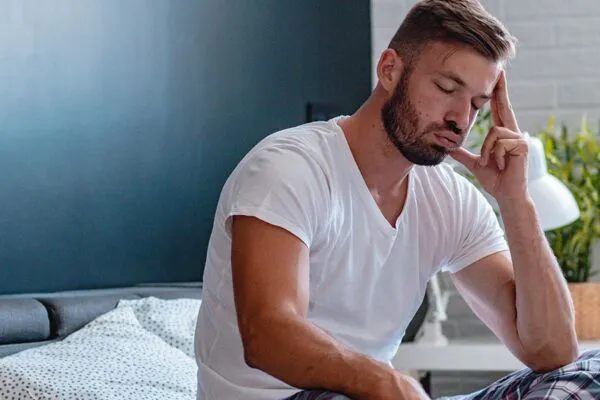 Young-man-on-his-bed-suffering-from-restlessness-which-is-one-of-the-symptoms-of-opioid-use.-600x400